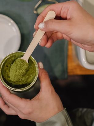 A person scooping vibrant matcha powder into a cup, perfect for cozy culinary scenes.