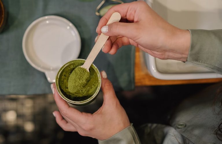 A person scooping vibrant matcha powder into a cup, perfect for cozy culinary scenes.