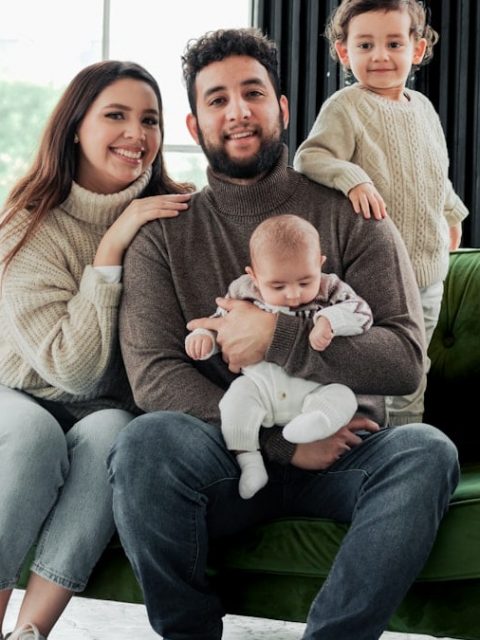 a family sitting on a green couch in a living room